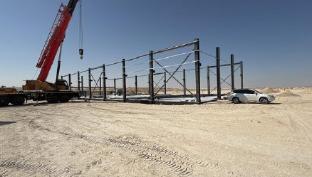 Crane lifting steelwork beside erected columns